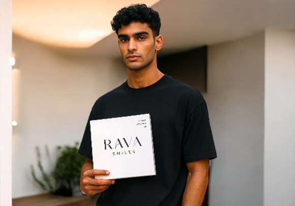 a man posing while holding Rava Smile's vaneer aftercare kit